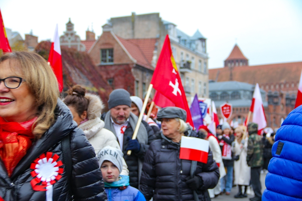 Gdańsk, Poland—11.11.2024: Polish paradegoers on traditional red-and-white rosettes on Poland National Day—commemorating national history through colorful symbols of unity and pride.