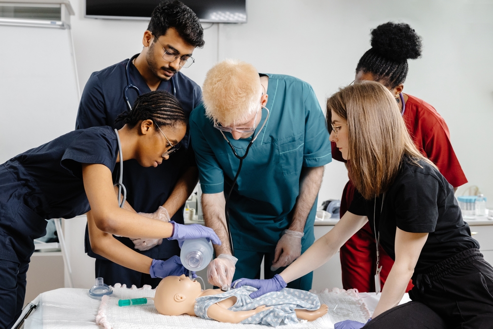 Diverse group of medical students practicing intubation on a baby mannequin, demonstrating essential skills in a simulated medical environment