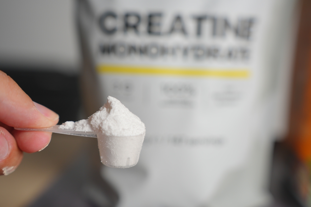 Heaped Scoop of Creatine Powder with Bag in Background