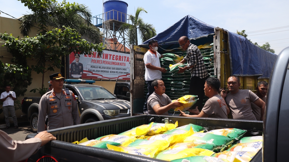 Police officers and volunteers unload and distribute rice aid from trucks as part of a government food security program to support the local community, Pekalongan, Indonesia August 13, 2025: