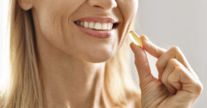 Doctor Shares Warning For Anyone Using Collagen Supplements woman taking soft gel supplement capsule