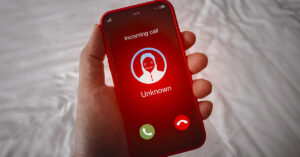 The Word That Can Turn Your Voice Into a Weapon for AI Fraud Scam call alert with red scammer icon as unknown caller, malicious phone calls concept. Unknown number Incoming displayed showing on smart mobile phone screen in person hand.