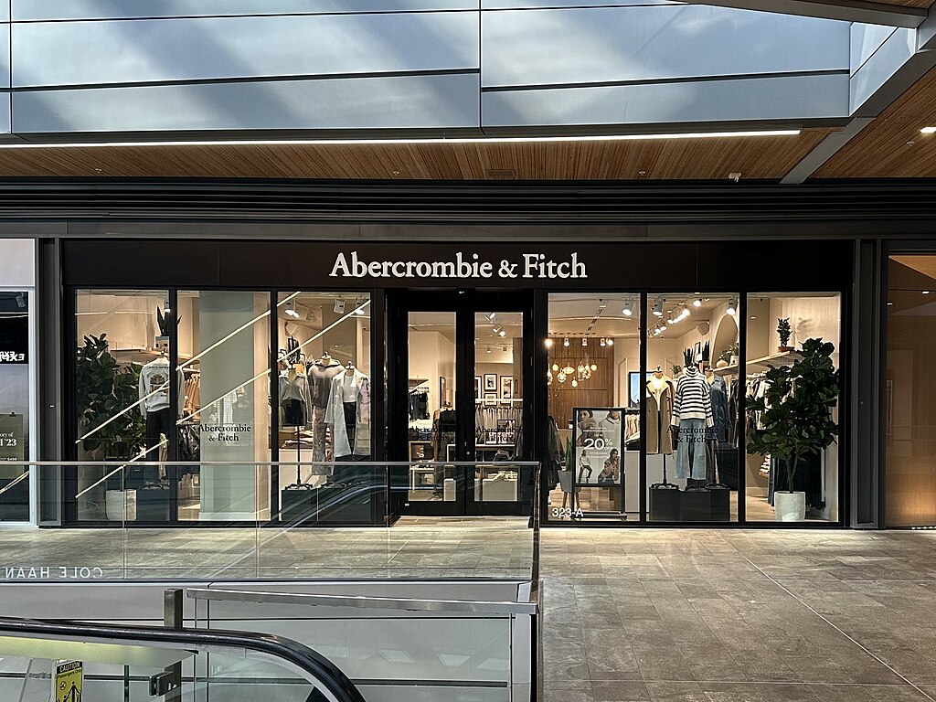 Abercrombie & Fitch storefront in a shopping mall with lit window displays showing clothing.