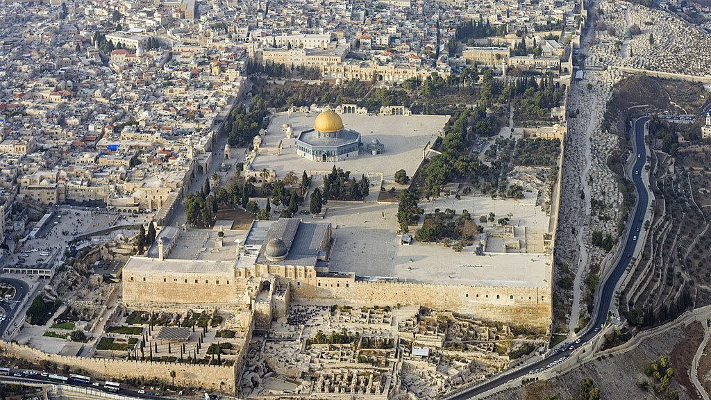 Aerial photograph of Jerusalem's Temple Mount, with the gold-domed Dome of the Rock at center and the Western Wall plaza visible at the bottom left corner of the compound.