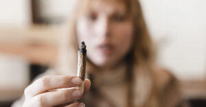 Woman holding up lit marijuana joint