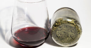 Glass of wine and a jar containing cannabis on its side