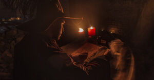 Young prophet Nostradamus writing his prophesies on a paper sitting in a ruined old church at night, high iso noise, low key, dark image