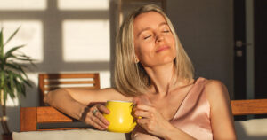12 Signs You’ve Already Achieved Success by Midlife woman basking in the sun while holding a yellow cup