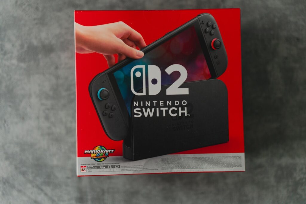 Nintendo Switch 2 product box in red packaging featuring an image of the console and Mario Kart branding.