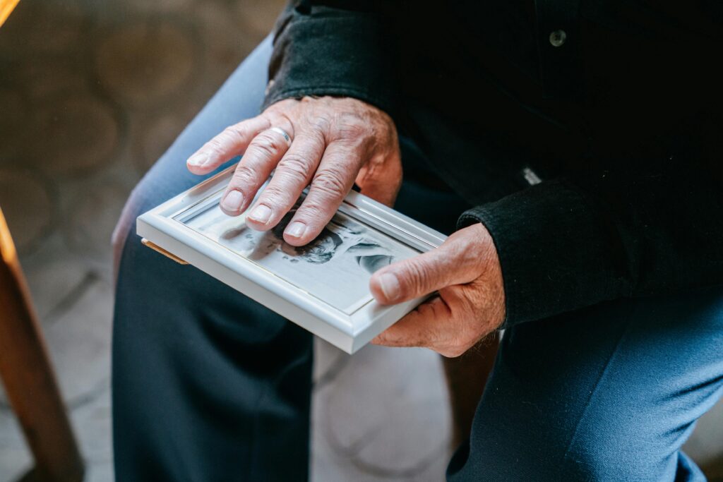 An elderly person's hands holding a small framed photograph.