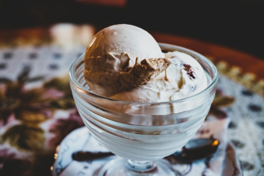 Scoops of chocolate and vanilla ice cream in a glass dessert bowl.