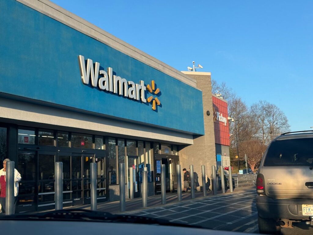 Walmart storefront with blue exterior and the company's yellow spark logo, parked car visible on a sunny day.