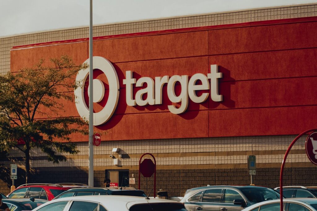 Target store exterior with red facade and white bullseye logo, cars scattered across the parking lot.