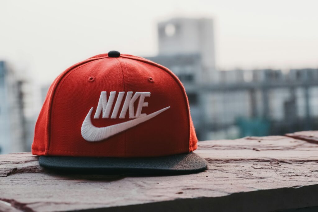 Red Nike snapback cap with white logo sitting on a ledge, blurry cityscape in the background.