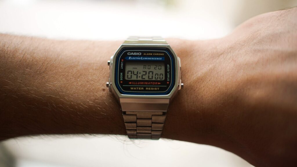 A silver Casio digital watch on a person's wrist displays the time: 04:20.