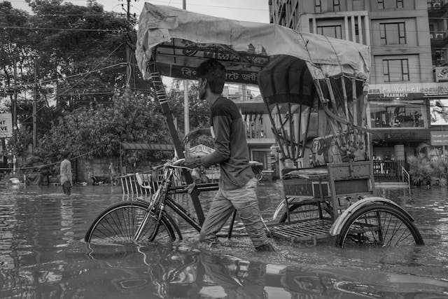 man puxhing bike hrough flooded street