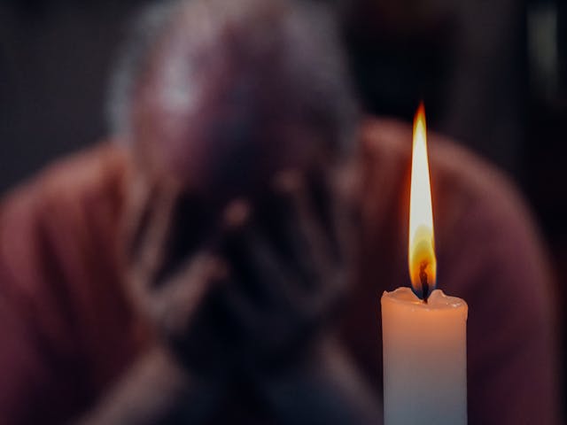 man with head in hands by candle