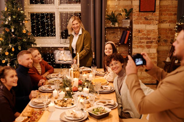 man taking photo of family at Christmas dinner