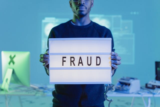 man holding a fraud sign