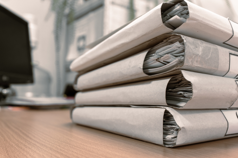 A stack of thick folders with documents on the table