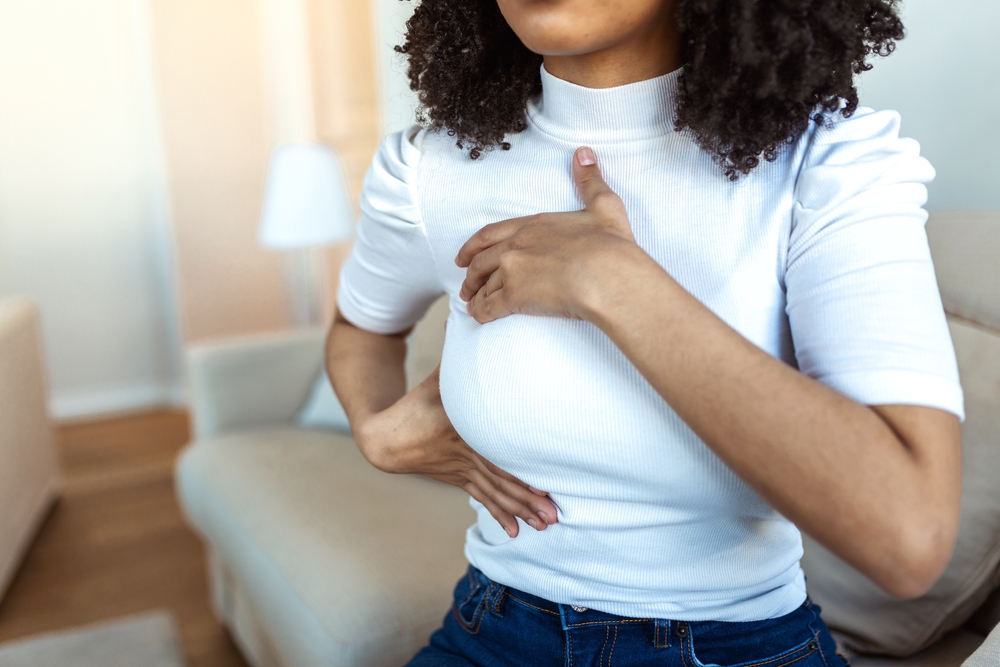 African American Woman hand checking lumps on her breast for signs of breast cancer. woman is suffering from pain in the breast. BSE or Breast Self-Exam. Guidelines to check for cancer.