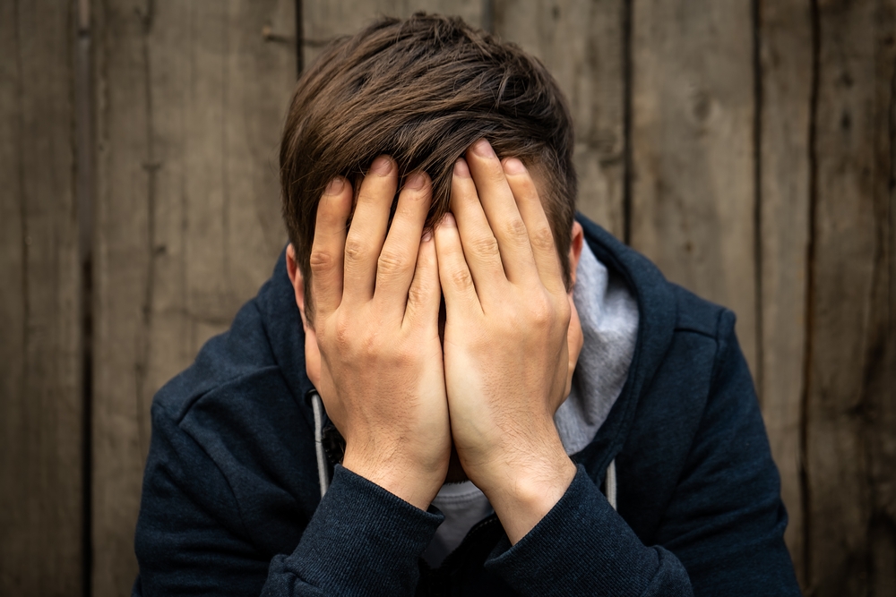 Sad Young Man on the Old Wooden Wall Background outdoor
