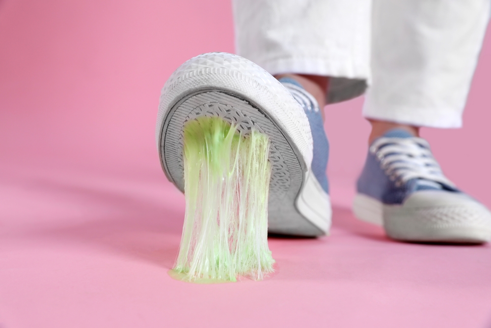 Person stepping into chewing gum on pink background, closeup