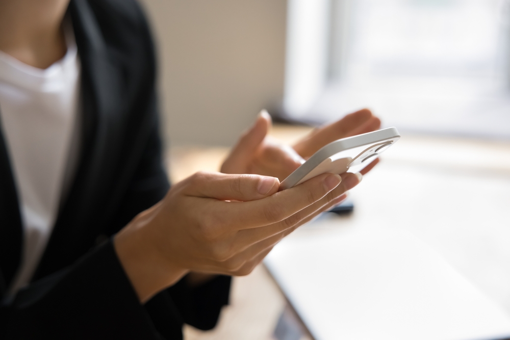 Close up shot of female hands holding smartphone. Young business woman using online application, service for communication, browsing Internet on mobile phone. Cropped shot