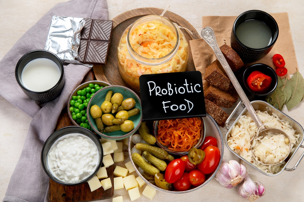 Probiotic food concept. Cabbage in jar, pickle, carrot on light wooden background. Top view
