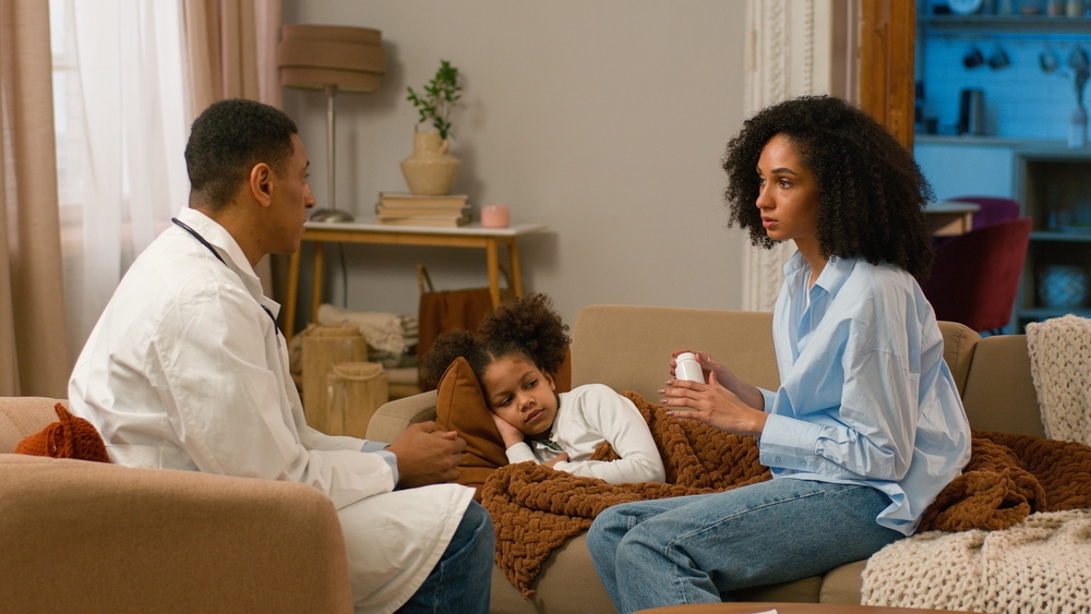 Man doctor giving medicine tablets antibiotics pills sick drug little girl daughter mother woman ill health child home parent treatment help patient pediatrician motherhood offspring unwell disease