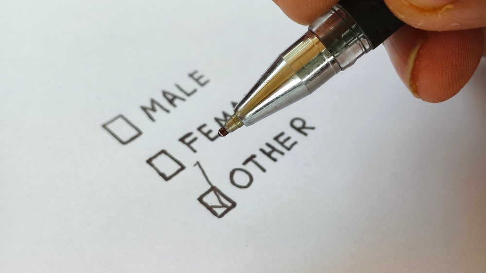 Close up of young asian or indian bigender or transgender person hand select other in gender identifying colums in a page. Concept of identity crisis.