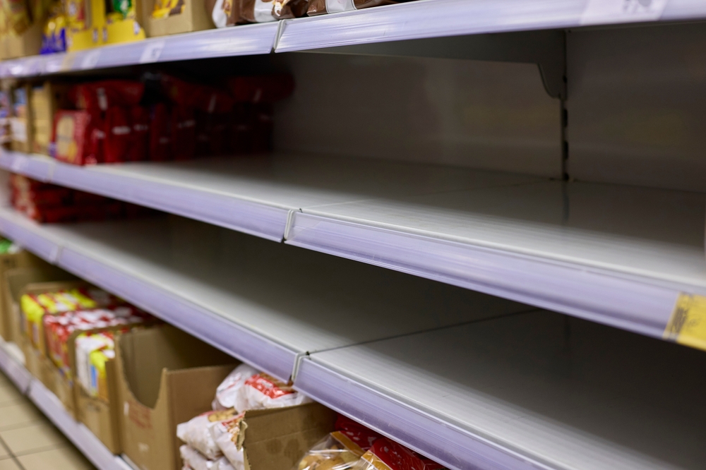 Empty grocery store shelves highlight a significant product shortage. The barren shelves are devoid of items, indicating reduced stock availability and potential supply chain issues.