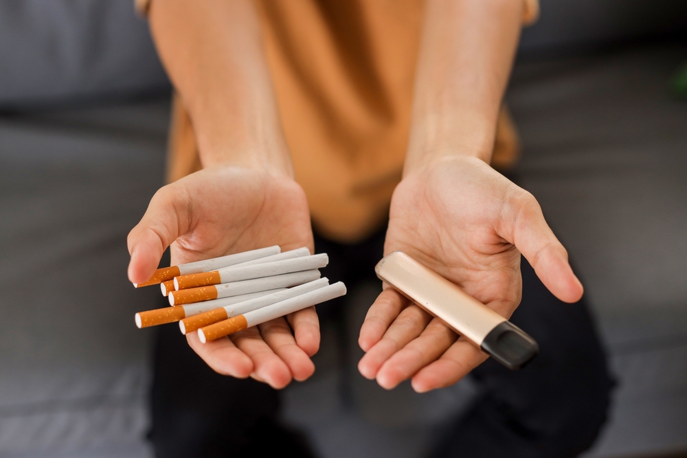 Cigarette vs e-cigarette concept. Man holding cigarette and vape.