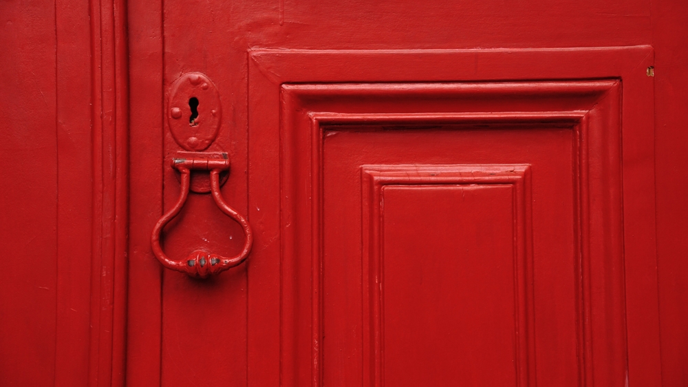 brass handle on wooden red door as background
