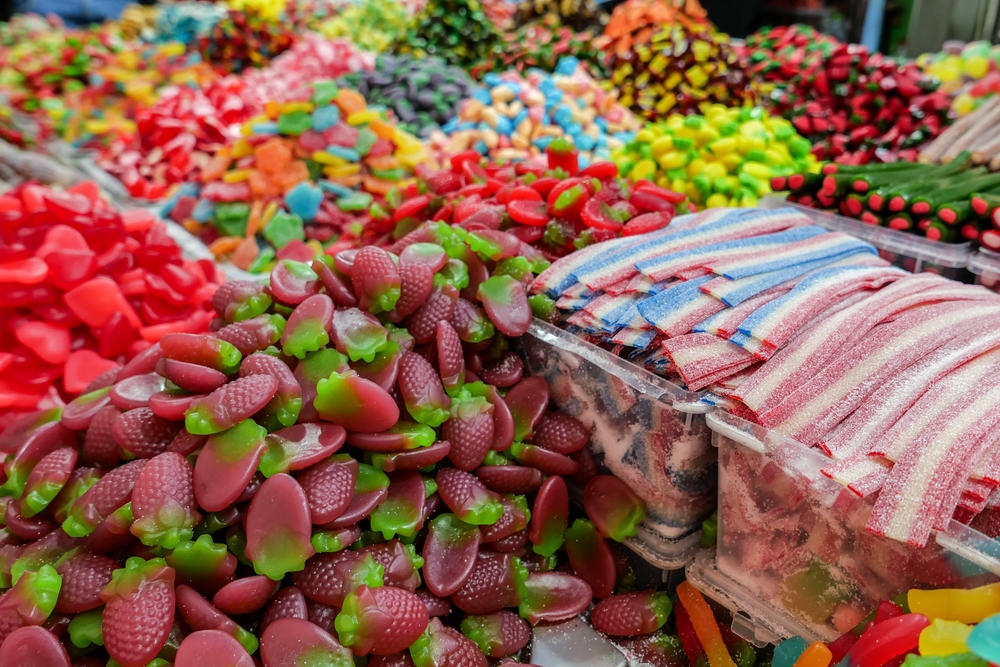 An assortment of colorful candies at a market stall, showing vivid artificial dyes soon to be banned by FDA regulation. Great visual for clean label and natural food trends.