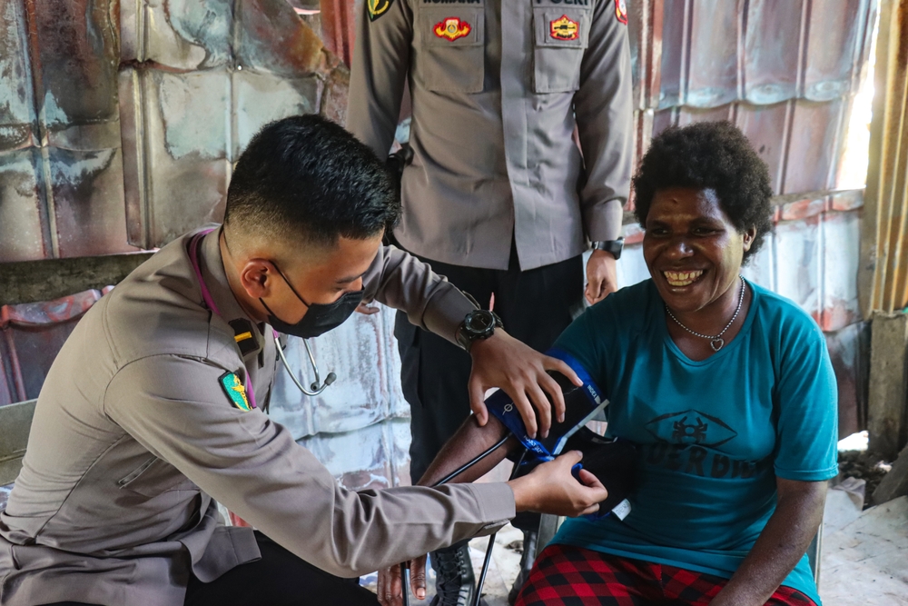 Yahukimo, Papua, Indonesia – February 2, 2022: A police officer conducts a medical check-up using a stethoscope on an indigenous in a rural community. highlights healthcare outreach and social care.