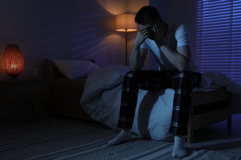 Frustrated man suffering from insomnia on bed indoors