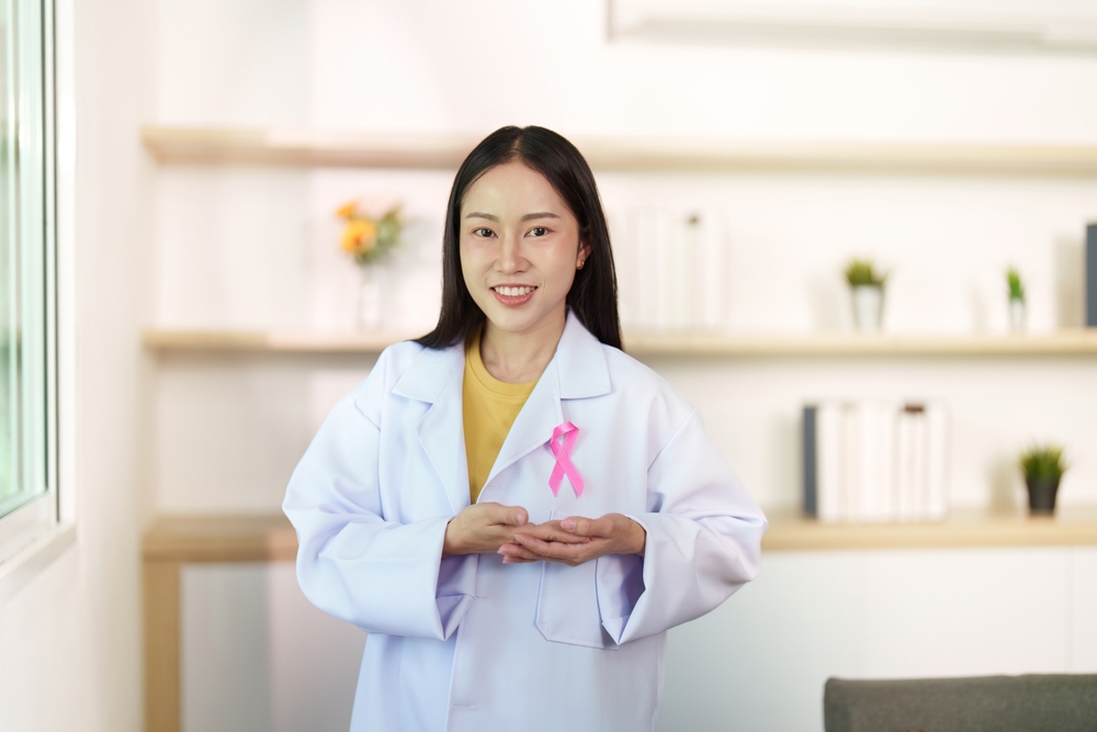 Breast Cancer Awareness. Smiling healthcare worker presenting pink ribbon.