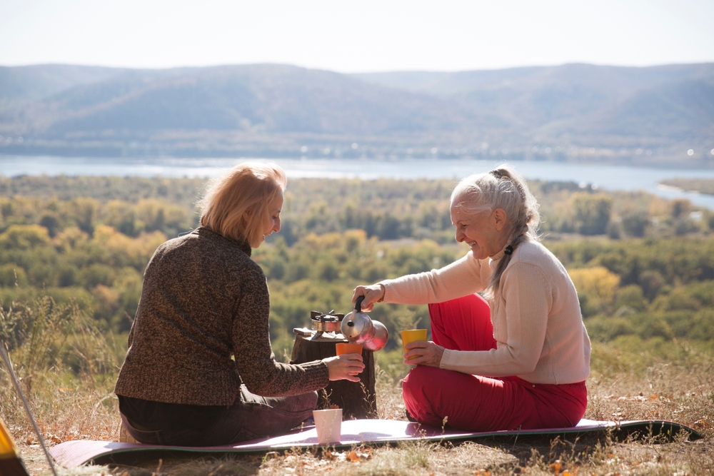 two women relaxing in  the mountain and brew coffee in Geyser coffee maker on a sunny autumn day.  Mindfulness and feel-good moments. spends time in nature. adult camp