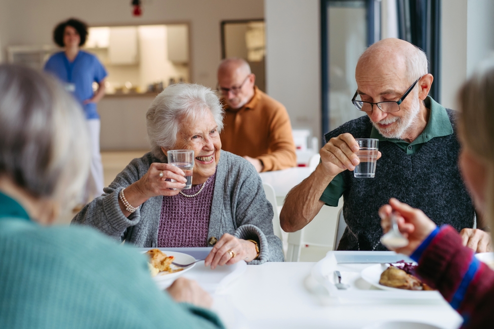 Group of seniors having lunch in community center cafeteria.