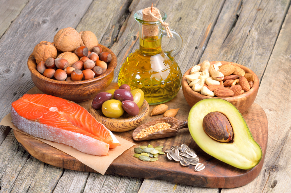 Selection of healthy fat sources on wooden background.