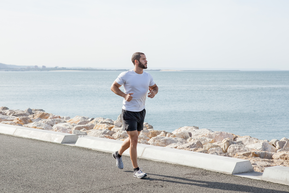 Serious Muscular Man Running on Seaside Road