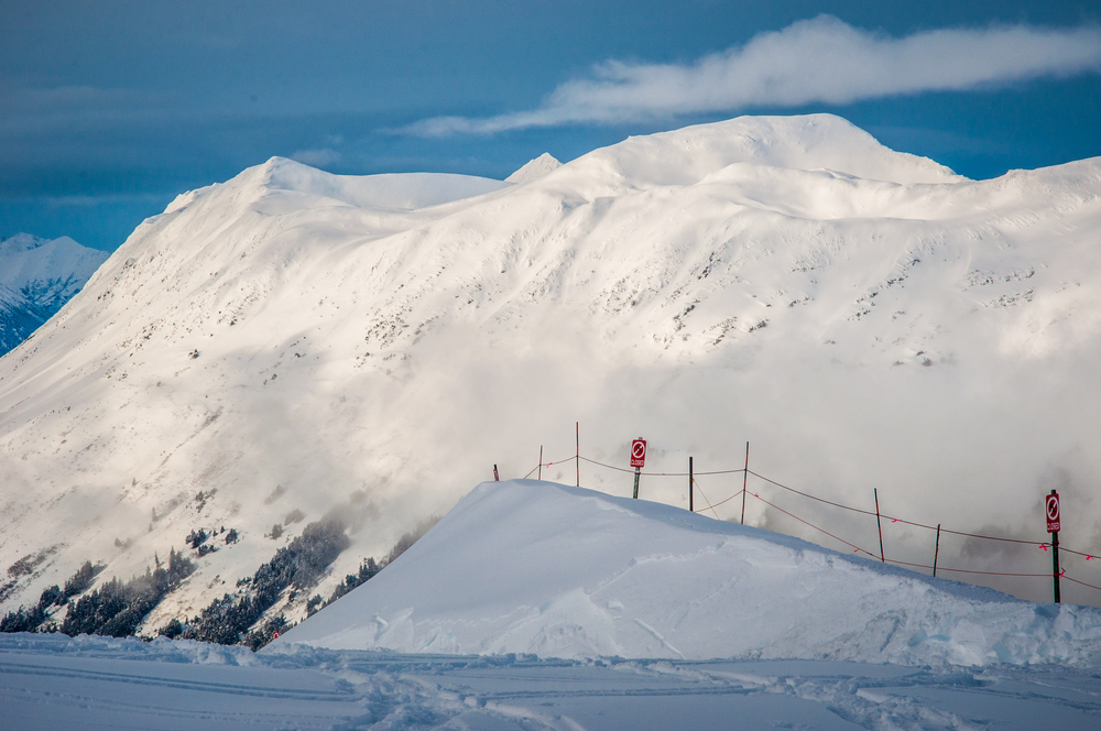 Pokryte śniegiem góry Alaski – zimowy krajobraz krainy czarów. Widok na dolinę Girdwood i stromą, ośnieżoną ścianę, gdy słońce wychodzi i świeci w Arktyce.