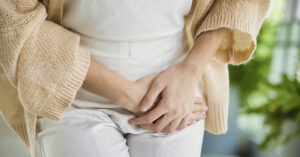 UTIs and Urinary Health: Symptoms, Natural Support, and Treatment Options Person holding lower abdomen with both hands, suggesting pelvic or urinary discomfort. UTI symptoms concept