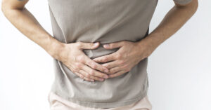 This Unexpected Food Causes More Food Poisoning Than Meat A man clutching his stomach in pain, possibly experiencing digestive issues, cramps, or discomfort related to health problems, Faceless