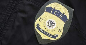 Minnesota Can Prosecute the ICE Shooter. A Trump Pardon Wouldn’t Stop It US ICE Officer badge on black uniform fabric surface close up