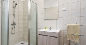 a clean, modern bathroom with a vanity, large mirror, and a glass-enclosed shower.