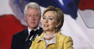 Hillary and Bill Clinton. Hillary Clinton in speaking at a podium with Bill Clinton in background