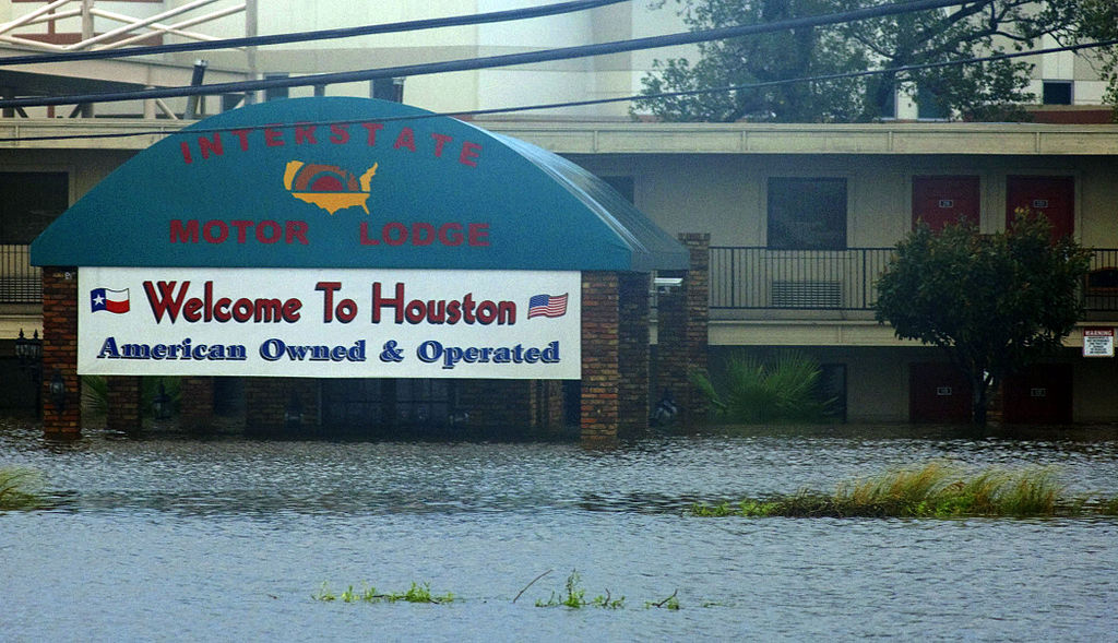 Floodwater reaches the base of a "Welcome to Houston" sign at the Interstate Motor Lodge, with the motel building visible behind it.