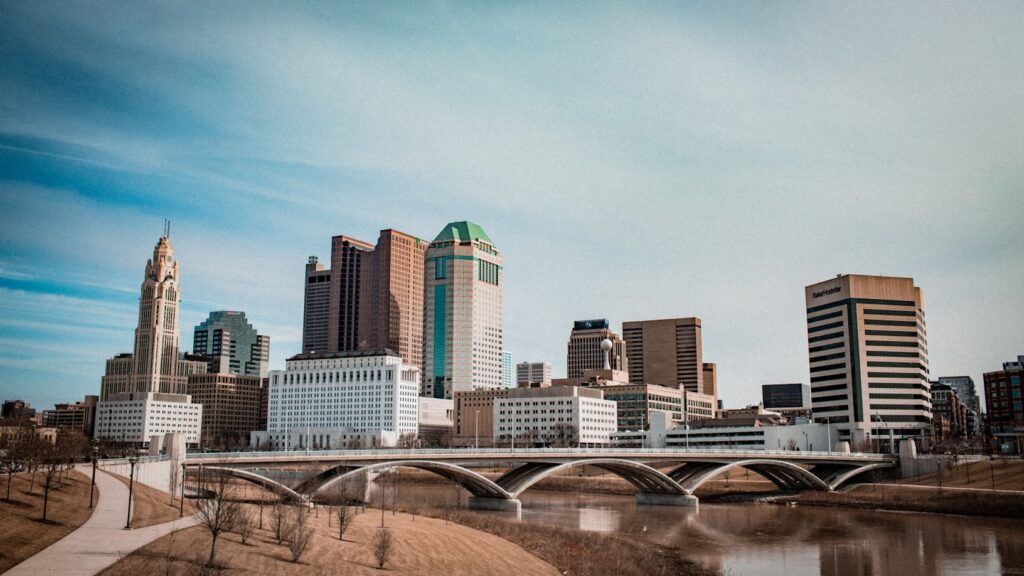 The Omaha skyline at dusk, with the First National Bank Tower and surrounding buildings reflected in still water below.